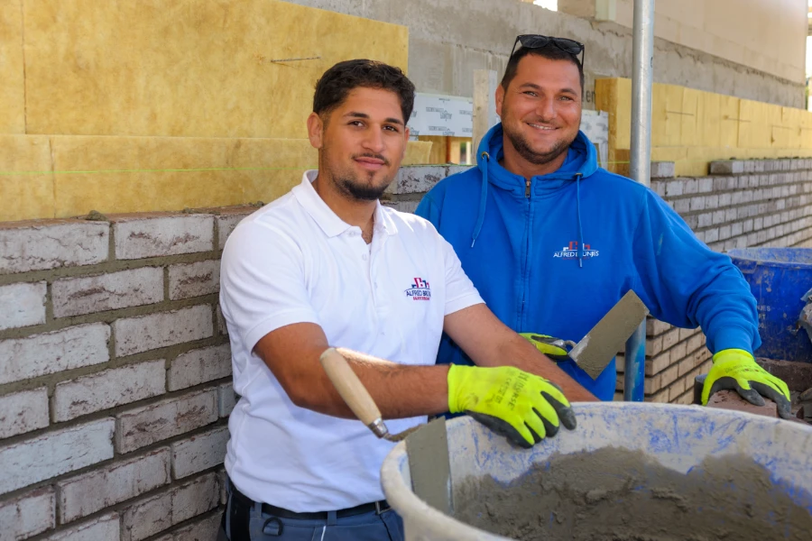 Zwei Mitarbeiter der Firma stehen an einem Eimer und lächeln in die Kamera