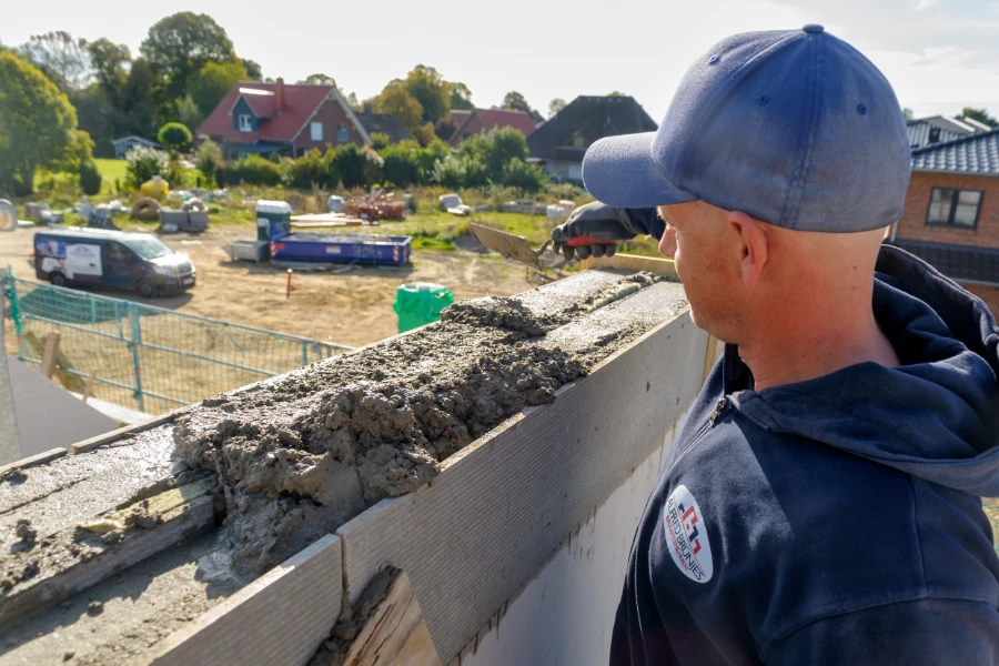Ein Maurer verteilt mit einem Spachtel Baumasse