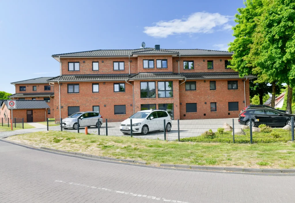 Ein Parkplatz mit Autos, im Hintergrund ein großes Mehrfamilienhaus