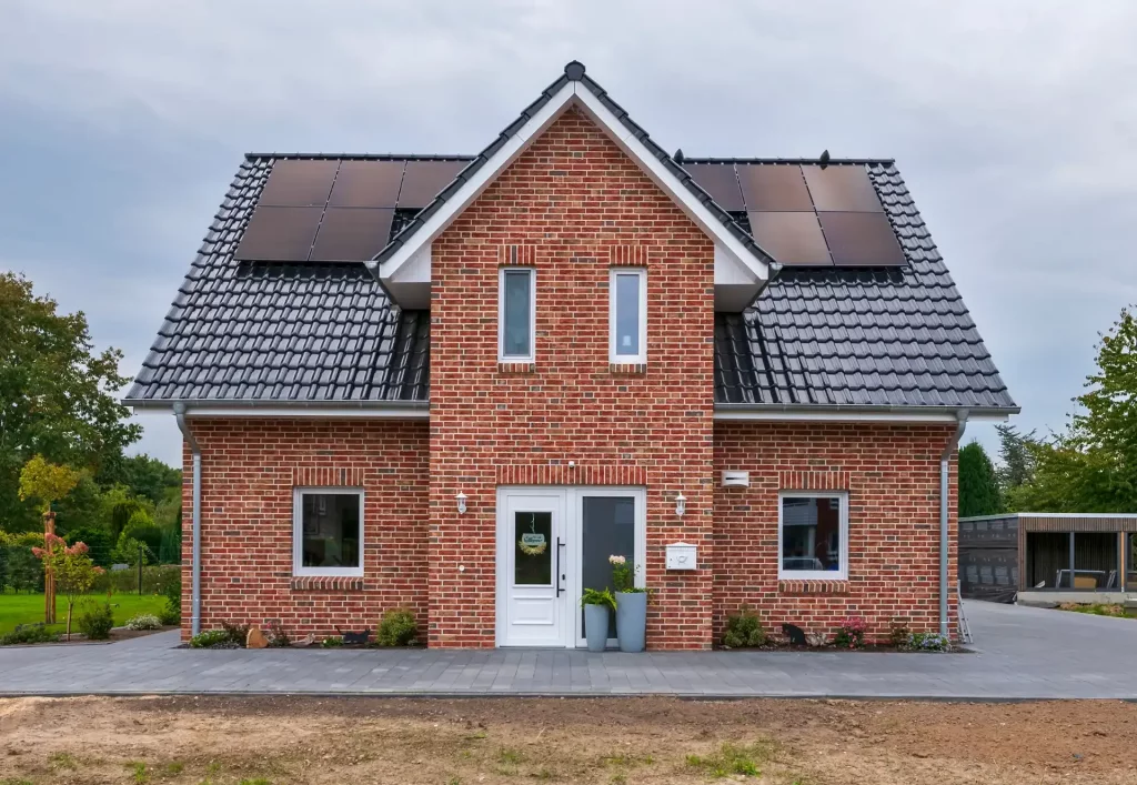 Ein rotes Einfamilienhaus mit Photovoltaik Anlage auf dem Dach