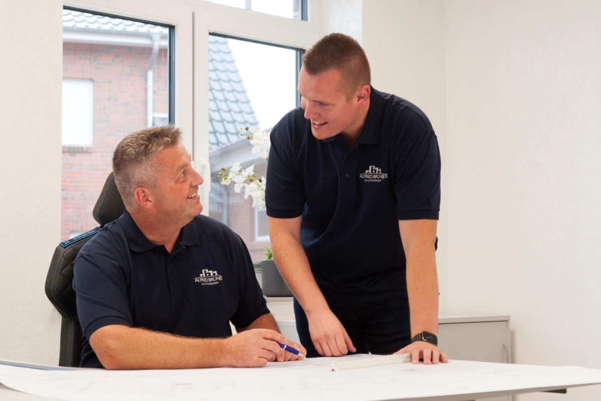 Zwei Mitarbeiter besprechen einen Bauplan.