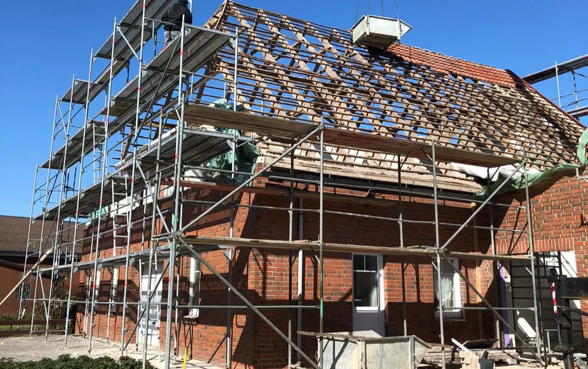 Ein Haus mit Baugerüsten, an dem gerade das Dach fertiggestellt wird.