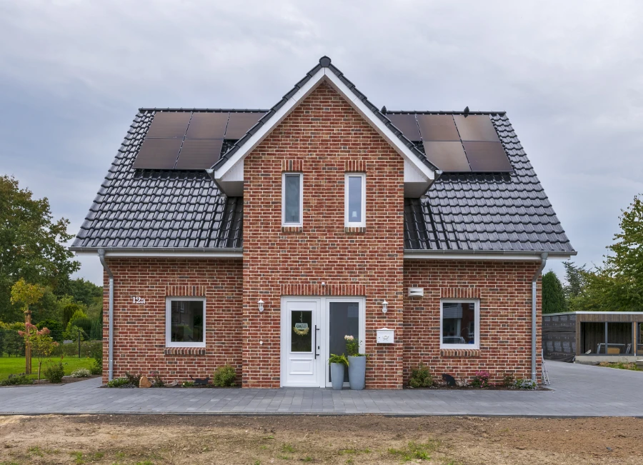 Frontansicht eines Einfamilienhauses mit Photovoltaik-Anlage auf dem Dach
