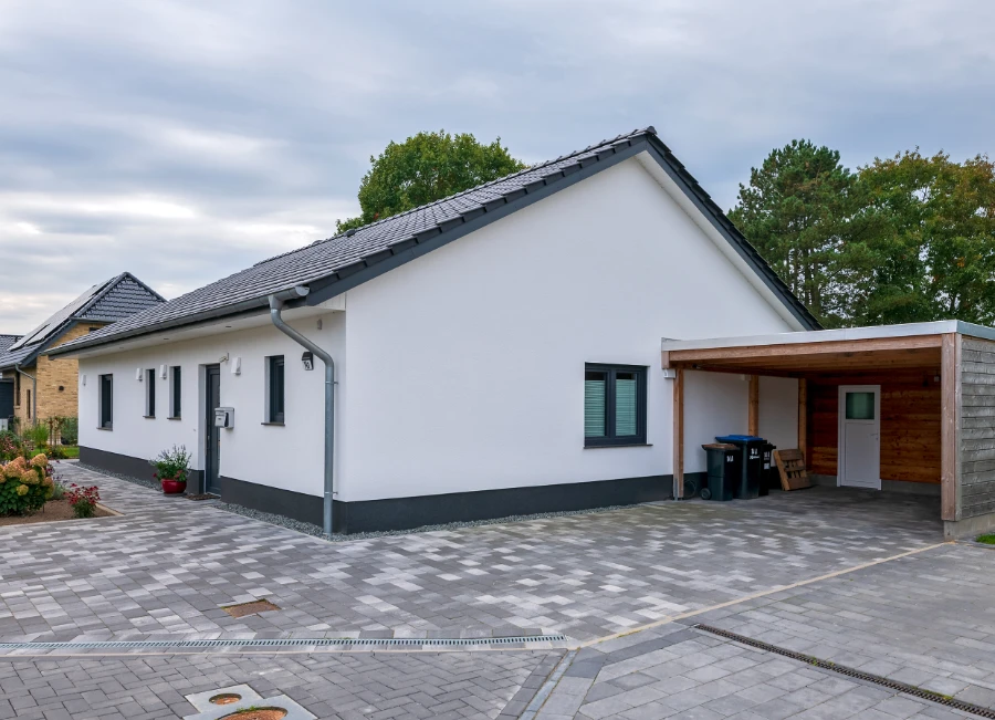Ein weißes Einfamilienhaus mit überdachtem Parkplatz
