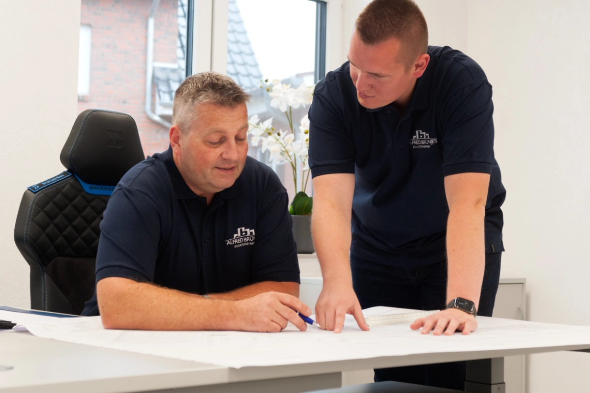 Zwei Mitarbeiter besprechen einen Bauplan.